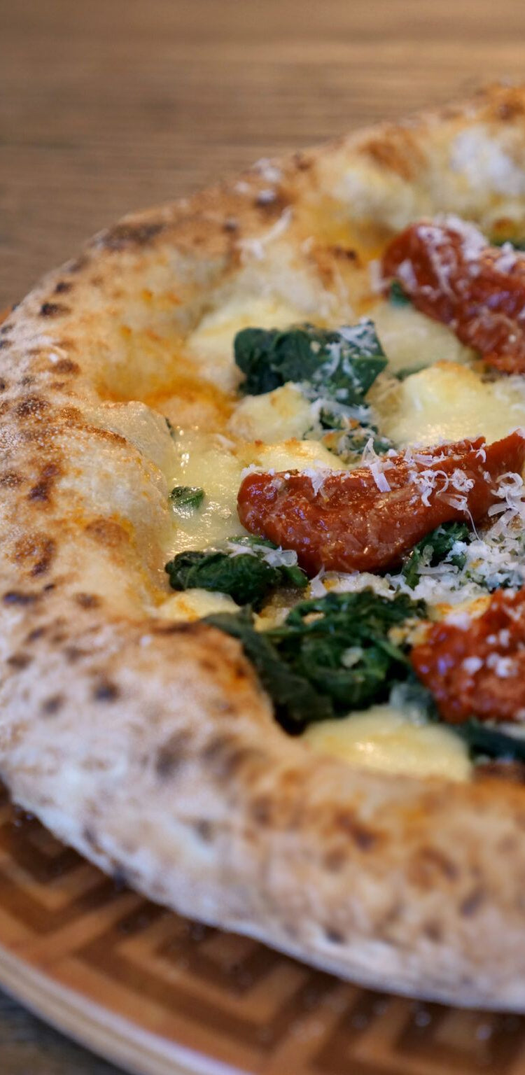 Pizza con verdure, pomodorini e mozzarella su un tagliere di legno