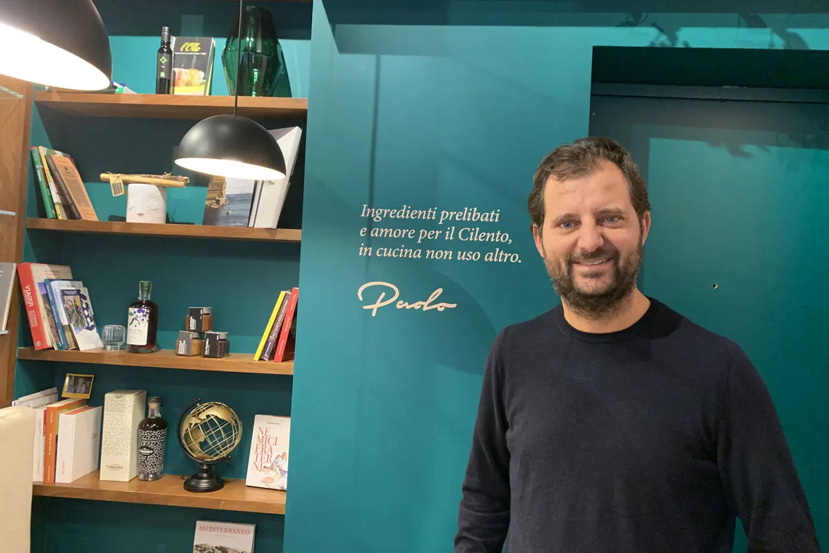 Paolo De Simone nella gastronomia Modus davanti alla parete con la sua firma