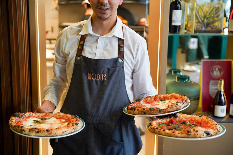 Cameriere di Modus con due pizze in mano