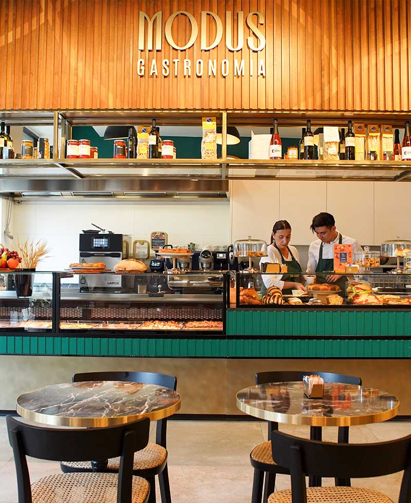 Interno di Modus Gastronomia con bancone, cucina a vista e tavolini