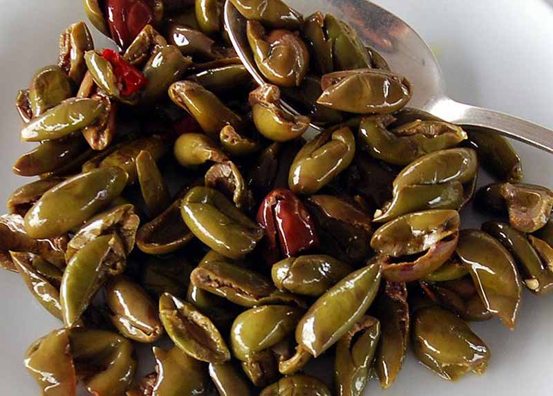 Olive ammaccate con peperoncino in un cucchiaio