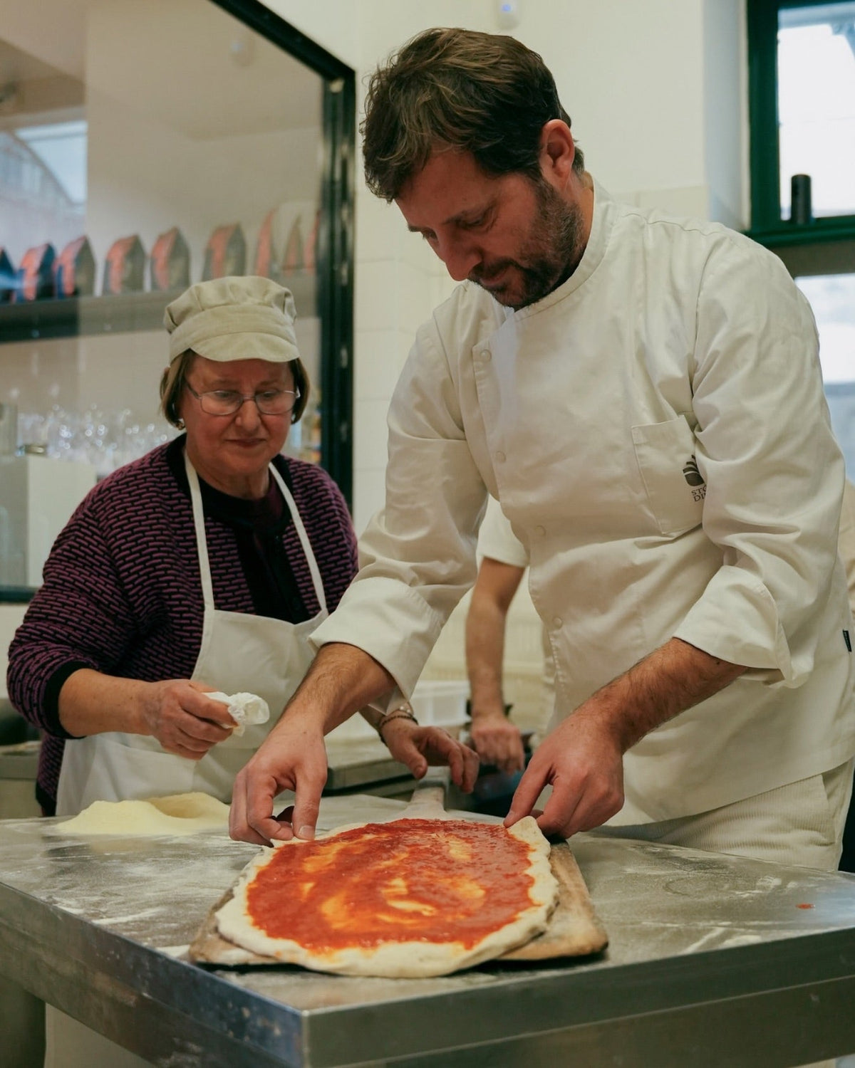 Paolo De Simone e una collaboratrice preparano una pizza
