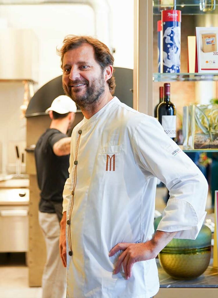 Paolo De Simone, in giacca da chef, davanti alla cucina di Modus