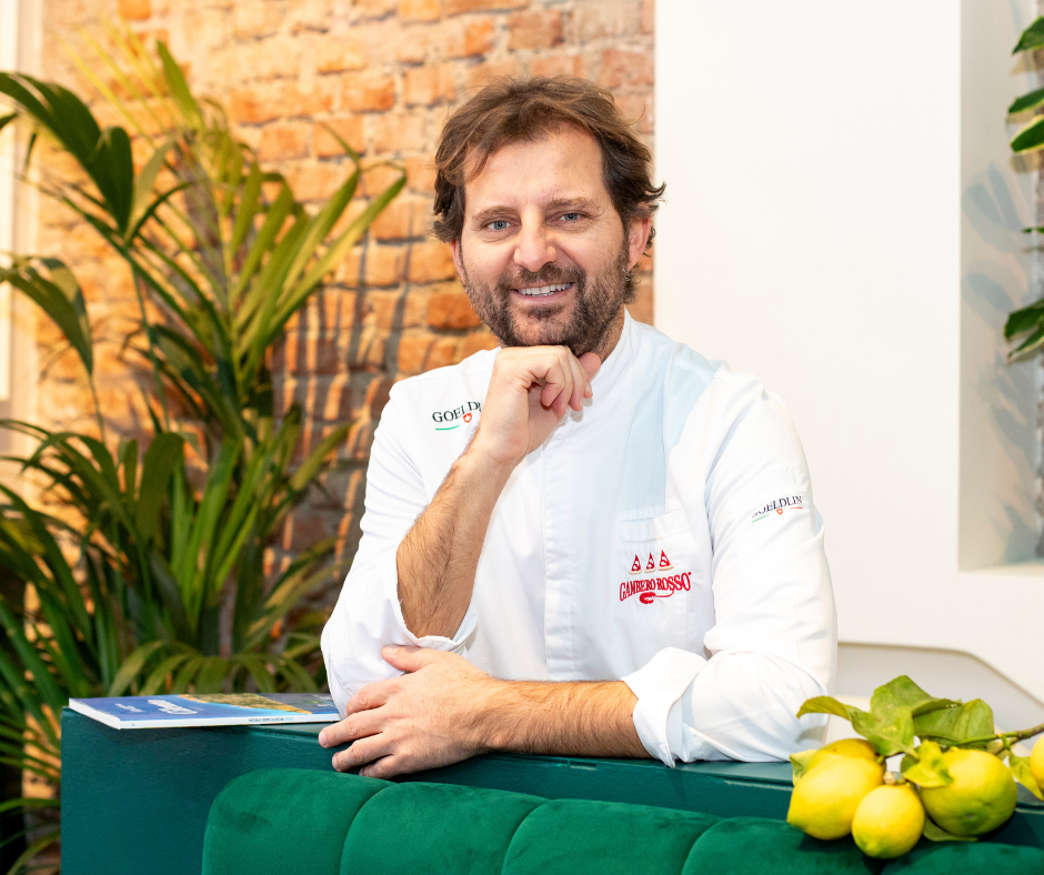 Paolo De Simone sorride con il mento appoggiato alla mano, con dei limoni accanto