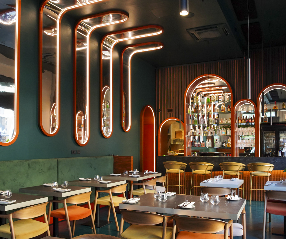 Sala della pizzeria Modus con luci a tubo, tavoli e sedie colorate