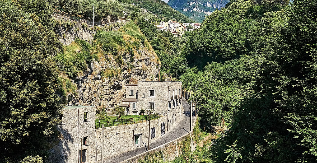 Strada tra rocce e vegetazione con un edificio in pietra